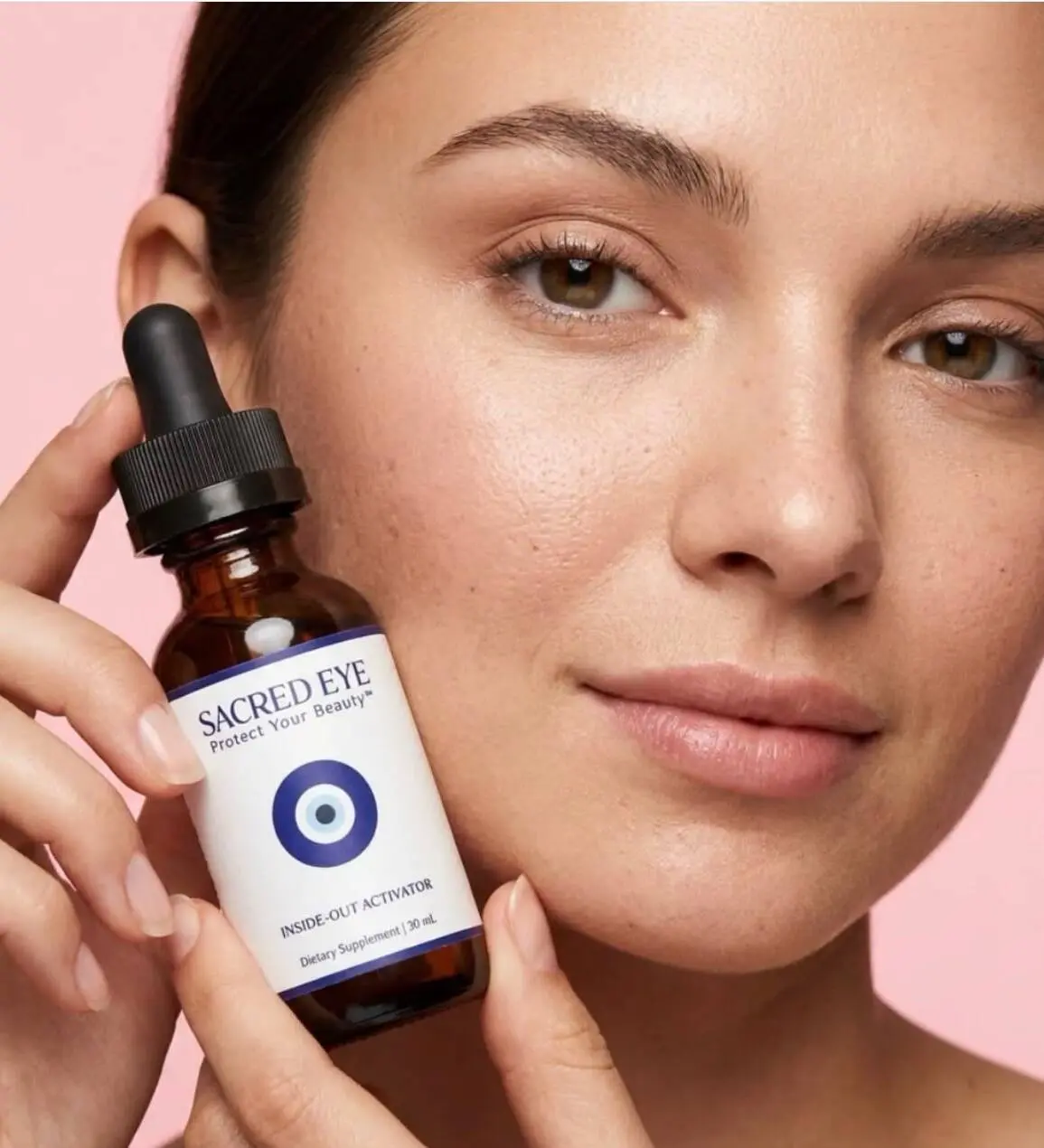 A woman holding the Sacred Eye Inside-Out Activator against her cheek